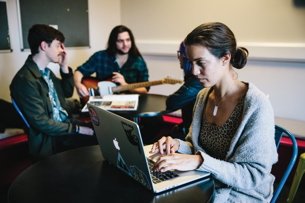 BIMM Students sitting down at a table using a laptop.