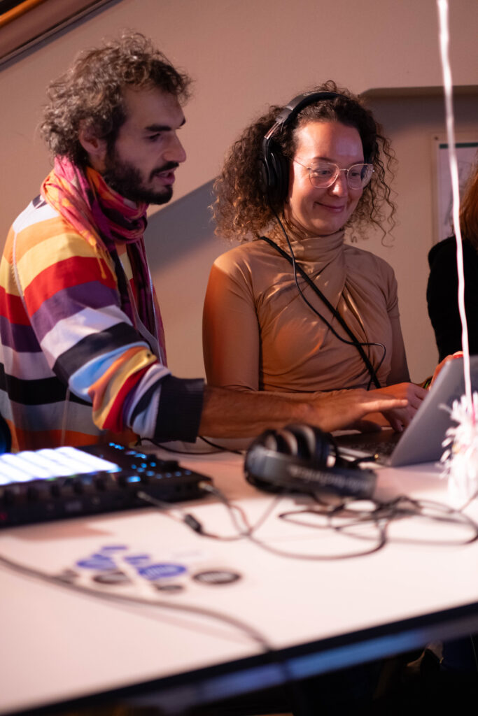 Image shows BIMM University Berlin lecturer Sjoerd van der Sanden standing next to one of the participants of Ableton's digital playground experience. They use the Ableton Push 3 and a computer to produce an electronic piece of music.