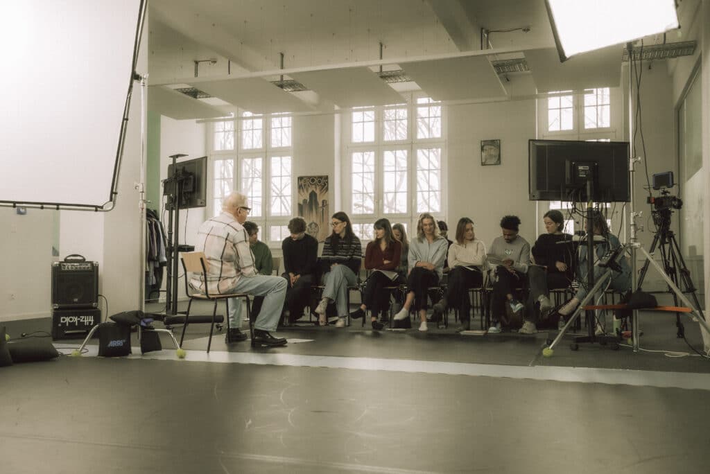 Mark Williams delivers small group workshop to BA (Hons) Acting for Stage, Screen and Digital Media students at BIMM University Berlin. Photo is taken from behind Mark, who is facing towards the line of acting students.