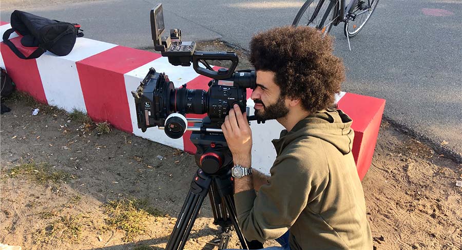 Student crouched down looking into a camera lengths