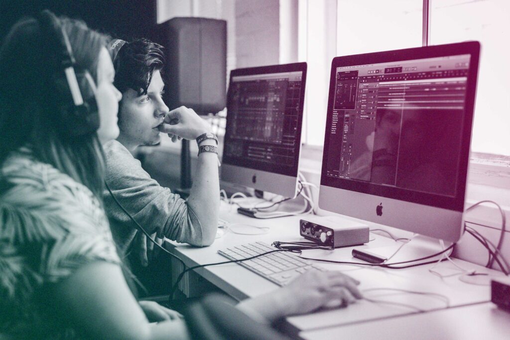 Students sit around music production software, editing some sound.