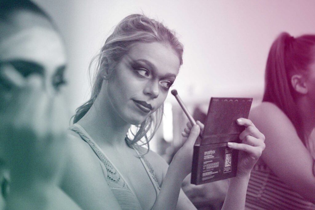An actor applies dramatic makeup around their eyes.