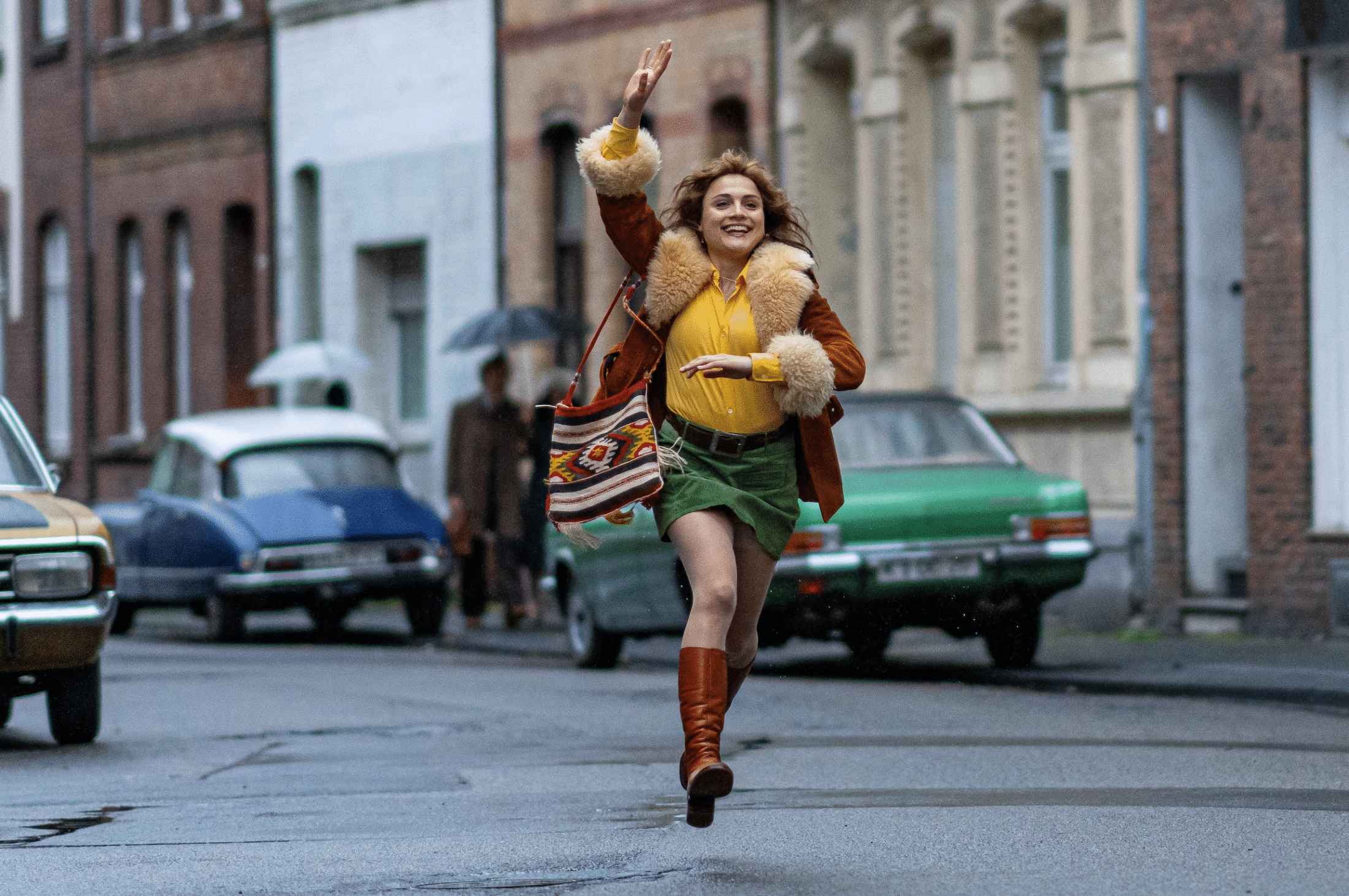 Film still from Köln 75 which depicts the main character Vera Brandes running down the street arm raised